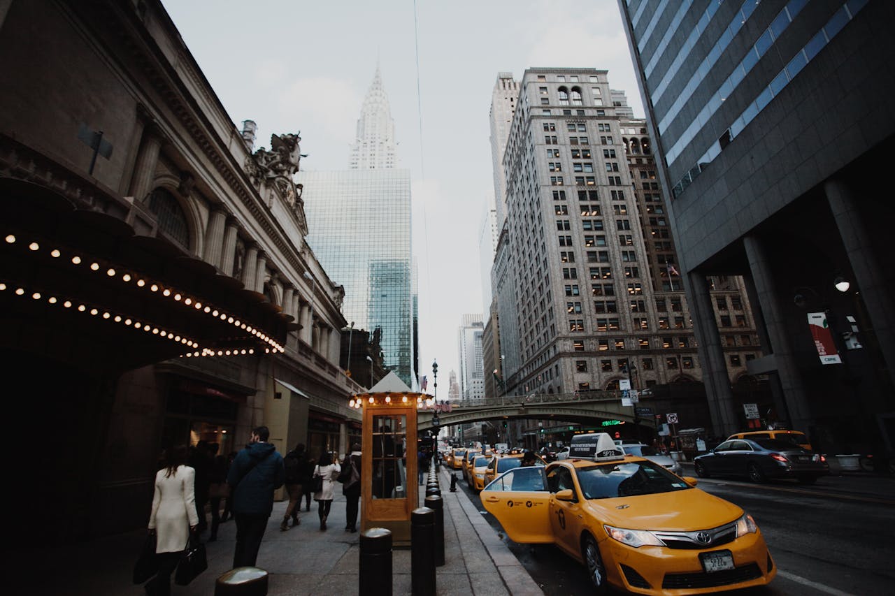 Dynamic view of a lively NYC street with iconic skyscrapers and yellow taxis.